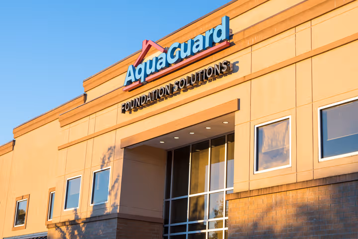 AquaGuard Foundation Solutions building exterior with company sign visible on a sunny day.