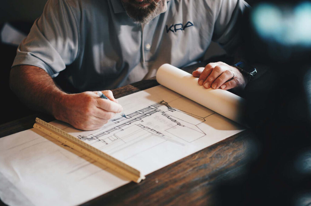 Architectural plans being drawn for Summit Electrical Group projects, with a pencil, ruler, and blueprints on a wooden desk.